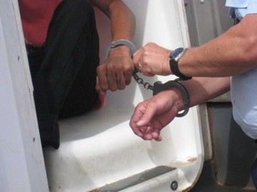 Photo of a youth being cuffed on exiting a transport van