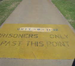 Image of path with painted text stating 'prisoners only past this point'.