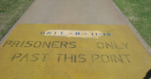 Image of path with painted text stating 'prisoners only past this point'.