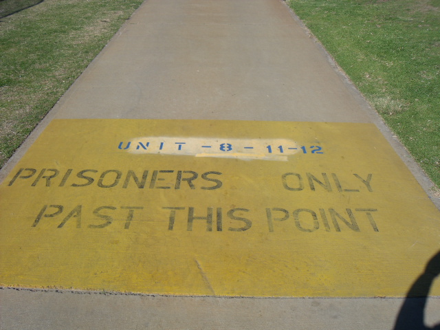 Image of path with painted text stating 'prisoners only past this point'.