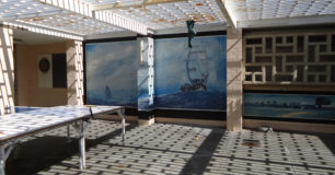 Photo of an outdoor exercise area, with a ping pong table and a large painting of a ship on the wall.