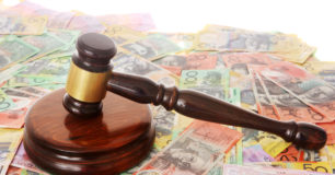 A judges gavel sitting on top of spread out Australian dollars