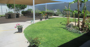 Image of the Gardens, with a shade sail over a BBQ and seating area within the Assisted Care Unit