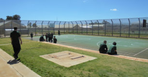 Image of prisoners sitting around the edge of a basketball court at Casuarina Prison.