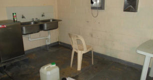 Image of part of the "recreation" area with a double sink, and a plastic chair by a telephone on the wall, for the maximum security prisoners at Broome Regional Prison
