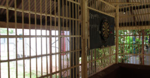 Image of a dartboard attached to the bars of the "bull-pen" outside area used for recreation at Broome Regional Prison