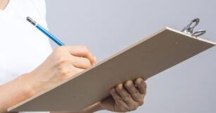 Image of a woman's hand holding a wooden clipboard