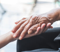 Older person's hand being held by carer