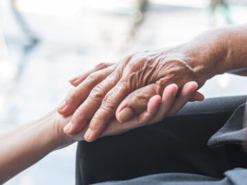 Older person's hand being held by carer