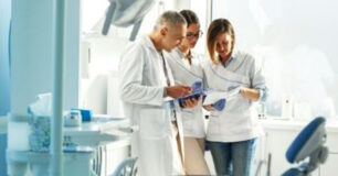 Image of a team of three dentists looking at notes.
