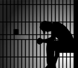 Image of a silhouette of a prisoner sitting down in a prison cell