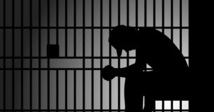 Image of a silhouette of a prisoner sitting down in a prison cell