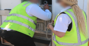 Image of officers adding restraints to a PIC through pod door hatch before boarding a transfer flight