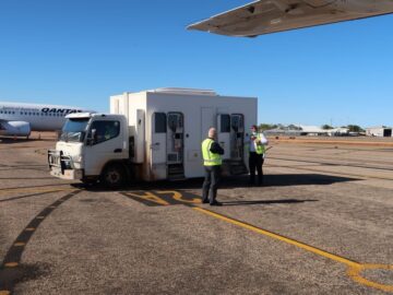 Image of a transport truck on airport tarmac ready to transfer prisoners