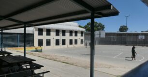 Image of an outdoor basketball court, with prisoners at recreation walking around the court