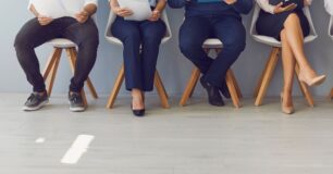 Image of a line of people sitting down waiting for job interviews.